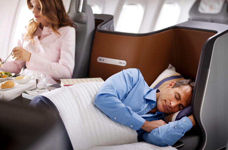 Ein Mann schläft im neuen Lufthansa Business Class Sitz, der zum Bett umfunktioniert ist.